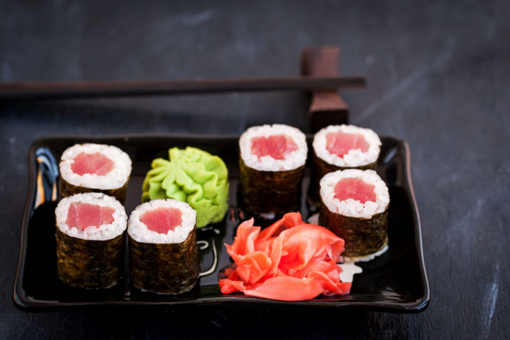 Sushi rolls on a dish with wasabi and ginger.